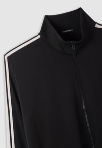 Giacca nera con zip e colletto alto a coste, con strisce bianche lungo le spalle e le maniche, taglia XL di Terranova.