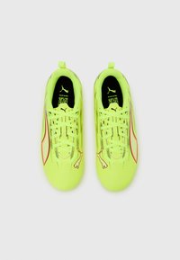 Zapatillas de fútbol de color amarillo neón con un diseño elegante, con detalles en negro, superficie texturizada y un distintivo logo de Puma en el lateral.
