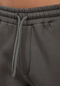 Grå bomulds joggers med snegltræk i taljen, med blød tekstur og sidelommer. Elastisk talje med samlede detaljer.