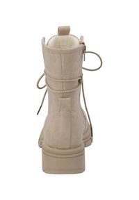 Botines de ante beige con punta redonda, diseño de cordones, tira trasera para el talón y suela de goma texturada. Presenta un tacón bajo en bloque.