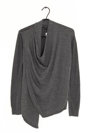 Pull à manches longues gris foncé avec devant drapé et détail de fermeture éclair sur l'épaule gauche, suspendu sur un cintre noir sur fond blanc.