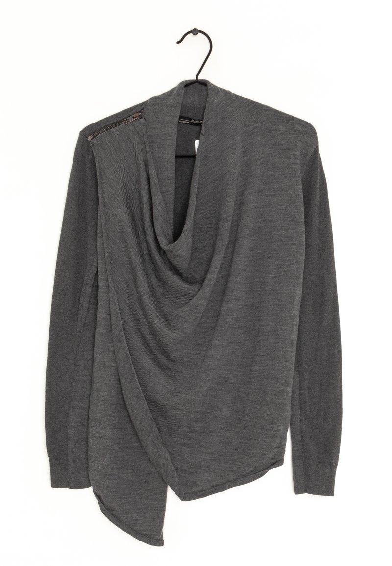 Pull à manches longues gris foncé avec devant drapé et détail de fermeture éclair sur l'épaule gauche, suspendu sur un cintre noir sur fond blanc.