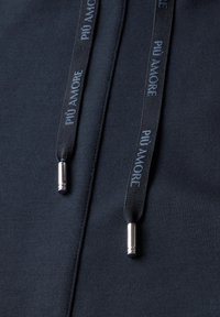 Detalle de sudadera navy con cordones negros marcados "PIÙ AMORE." Presenta puntas metálicas plateadas, textura de tela suave y un diseño sencillo.