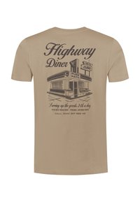 Beige t-shirt met een illustratie van een vintage diner, "Highway Diner," "Own the Journey," en contactgegevens gedrukt op de achterkant.