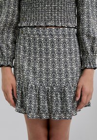 Falda con estampado en blanco y negro y dobladillo con volantes, hecha de tejido texturizado. Presenta una cinturilla con fruncido y botones decorativos.