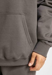 Gray sweatshirt with a front pocket, ribbed cuffs, and a hem. Smooth texture, relaxed fit, featuring minimal seams and a casual design.