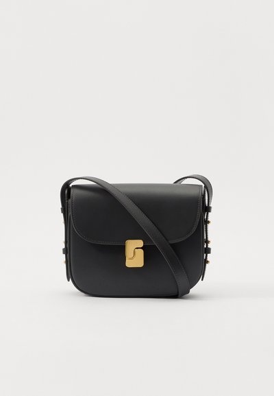 Sort læder crossbody taske med klap, guldsmykker og dekorative nitter langs siden. Har en justerbar rem for alsidighed.