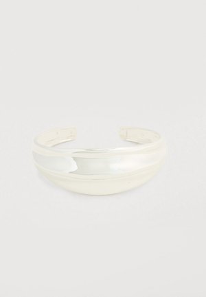 Brazalete rígido de metal plateado pulido. Presenta un diseño liso y redondeado con una banda ancha y curva, abierta en ambos extremos para un ajuste ajustable.