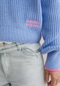 Maglione azzurro chiaro lavorato a maglia con orlo e polsini a coste, con la scritta ricamata in rosa "sending you love" sul lato inferiore sinistro.