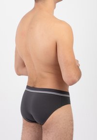 Boxer da uomo grigio scuro con una morbida vita elastica caratterizzata da una striscia grigia e bianca. Il tessuto è liscio e aderente.