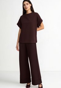 Top bordeaux, ampio, con maniche corte e pantaloni dritti. Tessuto liscio con una sottile lucentezza e design a gamba larga.