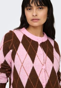 Braune und pinke Wollstrickjacke mit Diamantmuster, rundem Ausschnitt und Knöpfen entlang der Vorderseite. Weiche Textur mit gerippten Bündchen.