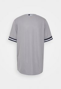Maillot de baseball gris à manches courtes vu de dos avec des poignets rayés noirs et blancs et logo MLB au col.