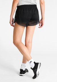 Los pantalones cortos deportivos negros presentan un diseño de malla con una cintura elástica, ofreciendo transpirabilidad y flexibilidad para el movimiento activo.