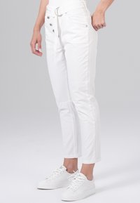 Witte katoenen broeken met een slim fit, voorzien van een hoge taille, knoopsluiting, voorkantzakken en een riemontwerp. Gecombineerd met witte sneakers.