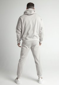 Conjunto de sudadera con capucha y pantalones jogger de patrón gris, hecho de tela suave, con capucha, puños acanalados y cinturilla elástica, combinado con zapatillas blancas.