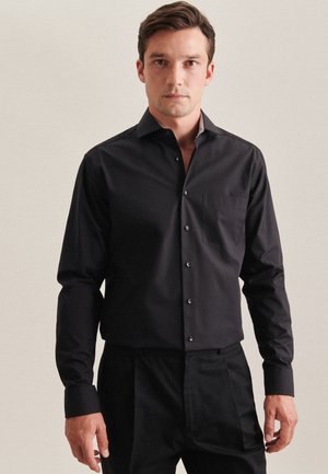 Black long-sleeve shirt with a button-up front, single chest pocket, and contrasting collar. Made from smooth, lightweight fabric.