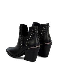 Botas de cuero negro hasta el tobillo con punta afilada, acentos con tachuelas en el lado y un tacón cuadrado con detalles metálicos.