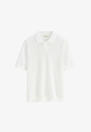 Polo shirt blanc à manches courtes en tissu texturé, avec un col classique, deux boutons, et des poignets et un ourlet côtelés.