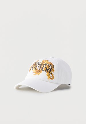 Hvit baseballcaps med svart "Versace Jeans Couture"-tekst og gullfarget ornamentert barokkdesign på frontpanelet, buet skygge og justerbar bak.