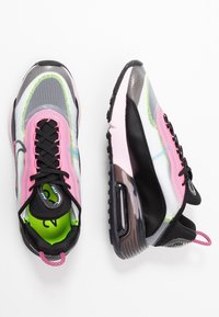 Nike-sneakers med ett genomskinligt mesh-överdel och svarta och rosa detaljer, livfull grön foder och en synlig luftenhet i sulan.