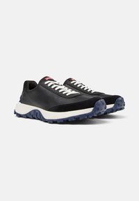 Scarpe sportive nere con lacci bianchi, caratterizzate da una tomaia testurizzata e una suola blu robusta, posizionate su uno sfondo bianco.