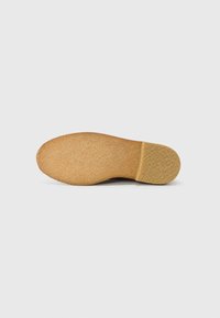 Brown rubber shoe sole with a textured finish. Slight heel, rounded toe, and a smooth edge. Light-colored and uniform pattern throughout.