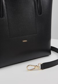 Svart pebblat läder tote-väska med en rektangulär framficka, guldfärgad detaljer och en avtagbar rem. Har präglad logotypdetalj.