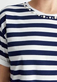Camiseta de rayas en algodón azul marino y blanco, con perlas decorativas y rhinestones a lo largo del escote. Mangas cortas y cuello redondo.