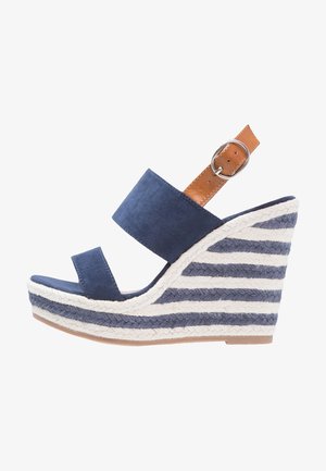 Granatowy zamszowy sandał na koturnie z dwoma paskami na cholewce, brązowym skórzanym paskiem na kostkę oraz plecioną, paskowaną podeszwą espadrylową w kolorze niebieskim i białym.