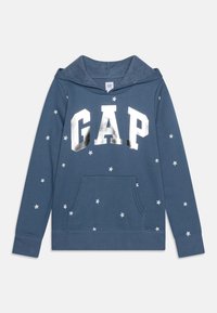 Felpa blu realizzata in morbido tessuto, con grande logo argentato "GAP" e motivi a stelle bianche. Include una tasca frontale e cappuccio.