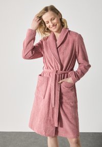 Rosa frotté badekåpe med sjalkrage, belte og to frontlommer. Myk tekstur, kne-lengde design og avslappet passform.