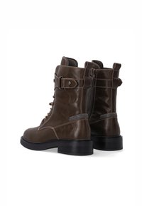Brązowe skórzane buty bojowe o eleganckim designie, z sznurówkami z przodu, bocznym zamkiem błyskawicznym i kontrastowymi detalami szwów. Gumowe podeszwy zapewniają stabilność.