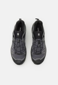 Szare buty sportowe z teksturowanym meshowym wierzchem, syntetycznymi nakładkami, elastycznymi sznurówkami oraz wyściełaną wkładką; wzmocnione obszary palców i pięty.