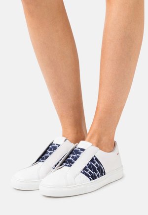 Baskets blanches à enfiler avec un bandeau élastique texturé bleu et blanc. Dotées d'une semelle en caoutchouc et d'un design minimaliste.