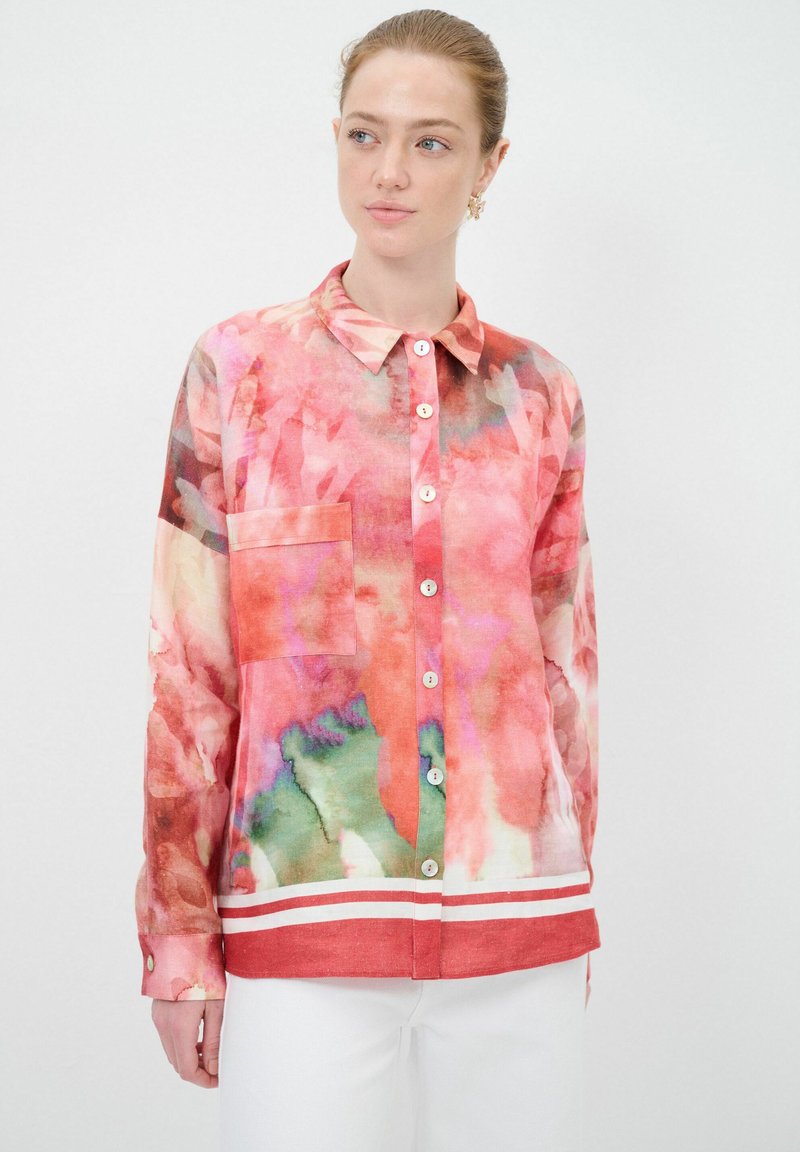 Camicia a maniche lunghe colorata con un motivo ad acquerello, caratterizzata da tonalità di rosa, verde e rosso. Include un bottone di chiusura, tasca e orlo a righe.