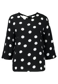 Blouse noire à pois blancs, manches 3/4, encolure ronde avec une ouverture en forme de goutte d'eau au dos. Texture de tissu lisse.