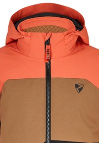 Orangene und braune Jacke mit hohem Kragen, schwarzem Reißverschluss und Logo-Akzenten. Strukturierte Innenseite mit einem Wabenmuster.
