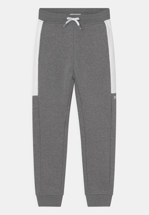 Grijze joggingbroek van zachte stof, met witte zijpanelen, een elastische tailleband met trekkoord en elastische boorden bij de enkels. Opvallende branding op het been.