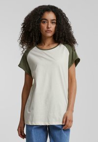 Kortermet T-skjorte i off-white med olivengrønne raglanermer og rund hals, laget av myk bomull.