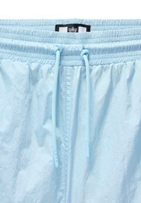 Lyseblå shorts med elastic waistband, justerbar snøre og en glat, let krøllet tekstur. Har et mærke øverst.