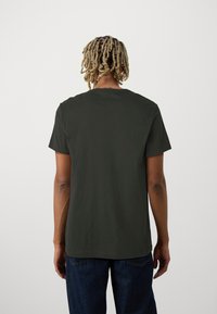Khaki grøn bomulds t-shirt med korte ærmer, rund halsudskæring og en afslappet pasform. Har en glat tekstur og enkelt design på en ensfarvet baggrund.