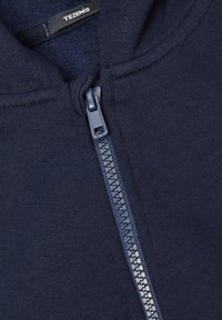 Granatowa bluza rozpinana z gładkiego materiału, z plastikowym zamkiem błyskawicznym i metką oznaczoną "TEZENIS" przy szyi.