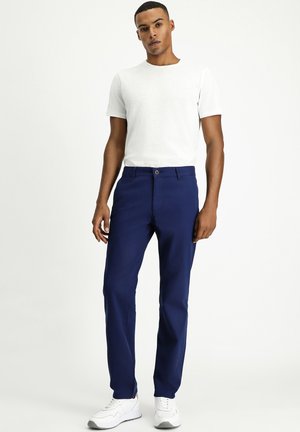Pantalones azul marino con corte recto, hechos de algodón. Presentan un cierre de botón y bolsillos laterales, combinados con una camiseta blanca de cuello redondo.