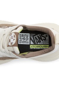 Scarpe Vans con una tomaia beige e bianca, accenti in suede testurizzato, collo imbottito e logo verde sulla soletta con dettagli di codice QR.