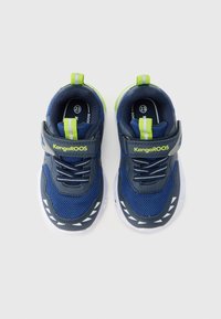 Μπλε αθλητικά παπούτσια από διχτυωτό υλικό με γκρι λεπτ ομέρειες, λευκή σόλα, ανακλαστικές λεπτομέρειες, ιμάντα με βέλκρο και πράσινη ετικέτα στη φτέρνα. Κατάλληλα για καθημερινή χρήση.