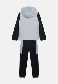 Παιδικό σετ φόρμας δύο τεμαχίων με μακρυμάνικο μαύρο πάνω μέρος και παντελόνι, γκρι ανοιχτό γιλέκο με κουκούλα και ταιριαστά γκρι πλαϊνά πάνελ στο παντελόνι.
