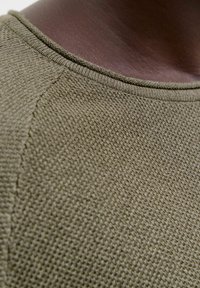 Olivgrön texturerad stickad tröja med rund halsringning och diskret sömdetalj, som visar ett mjukt, luftigt tyg.