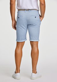 Ljusblå shorts med ett strukturerat mönster, rullade fållar, två bakfickor och ett vävt bälte. Kombinerat med vita sneakers.