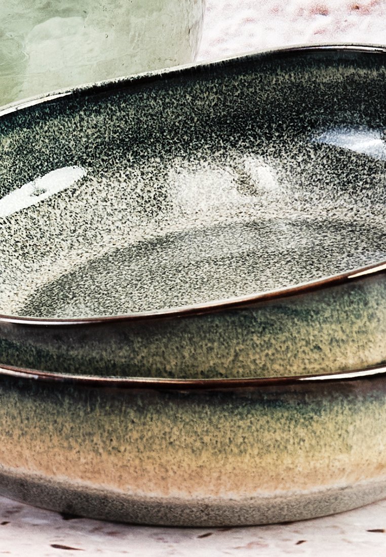 Gestapelte Keramiken mit einer gesprenkelten grün-beigen Glasur, die eine glatte Textur und ein dezentes Farbverlaufdesign aufweisen.